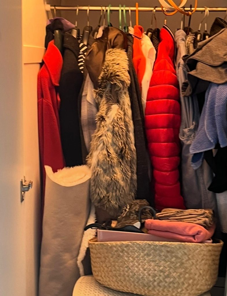 Small closet with clothes, bags and random items creating clutter